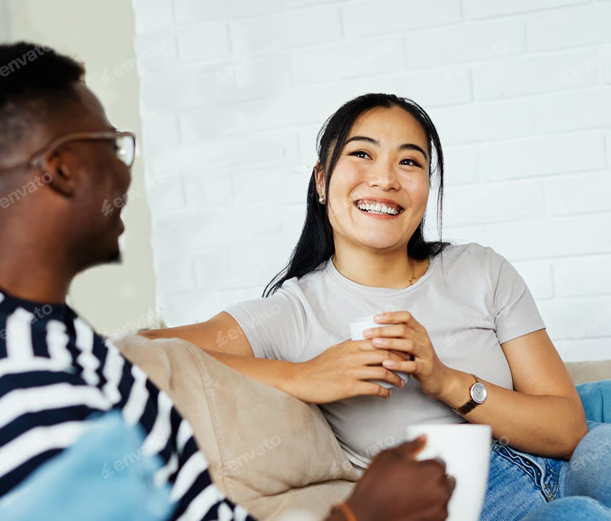 Two people having a relaxed conversation on a sofa with mugs